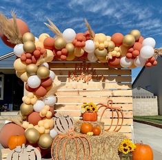 an outdoor display with pumpkins, hay bales and balloons