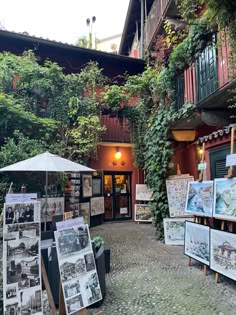 an open air museum with paintings and pictures on display in the foreground, surrounded by greenery