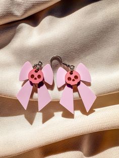 Add a touch of playful goth to your style with these adorable Pastel Bow and Skull Earrings! Featuring a charming combination of a light pastel purple bow and a pastel hot pink skull, these earrings are perfect for anyone who loves unique, eye-catching accessories. Size: Approximately 1.5" tall. Colors: Light pastel purple bow and pastel hot pink skull. Materials: Durable acrylic. Lightweight & Comfortable: Designed for all-day wear. Gift-Ready Packaging: Each pair is carefully packed in paper shavings and shipped in a protective box, ready to be gifted. These earrings are perfect for adding a fun pop of color to your outfit, whether you're dressing up for a special occasion or adding a bit of flair to your everyday look! Pink Bow Earrings In Cute Style, Cute Pink Earrings With Pink Bow, Pink Halloween Party Earrings, Pastell Pink, Pastel Goth Earrings, Cloud Jewelry, Light Pastel Purple, Pastel Skull, Pastel Bows