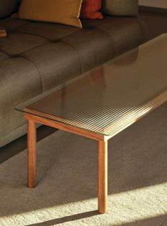 a glass coffee table sitting on top of a carpeted floor next to a couch