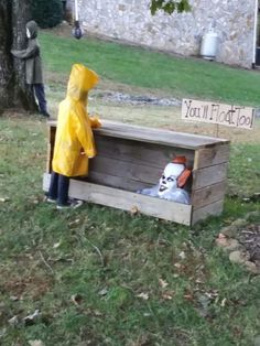 a person in a yellow raincoat standing next to a wooden box with an image of a clown on it