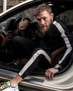 a man sitting in the driver's seat of a car with his hand on the steering wheel