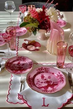 the table is set with pink and white dishes