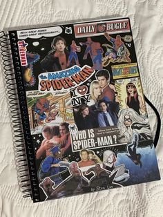 a spiral notebook covered in stickers on top of a bed