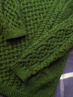 a green knitted blanket laying on top of a bed