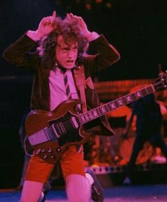 an image of a man that is playing the guitar on stage with his hands behind his head