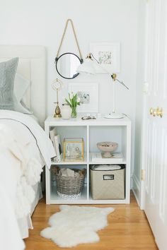 a bedroom with a white bed and some baskets on the shelf in front of it