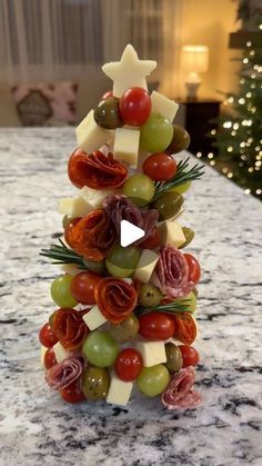 a christmas tree made out of grapes, cheese and meats on a marble counter top