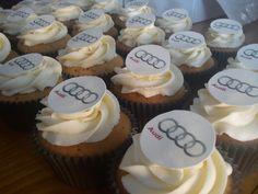 cupcakes with white frosting and an audi logo on them are arranged in rows