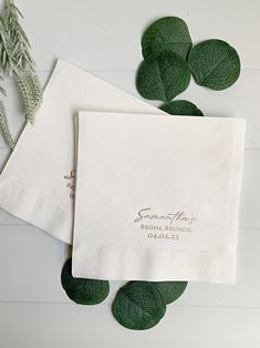 two personalized napkins on top of each other next to green leaves and greenery