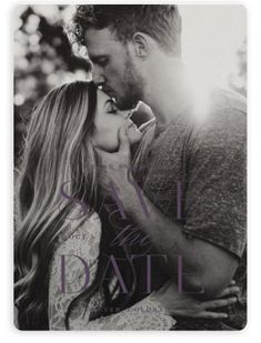 a man and woman kissing each other in the grass with trees in the back ground