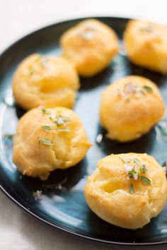 several small rolls on a black plate with herbs