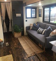 a living room filled with furniture next to a window covered in curtains and rugs