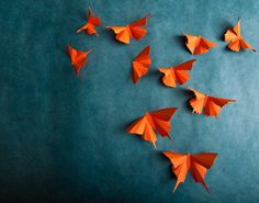 several orange origami butterflies on a blue background