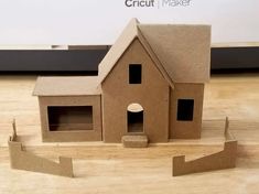 a cardboard house sitting on top of a wooden floor next to a wall with the words circuit maker written above it