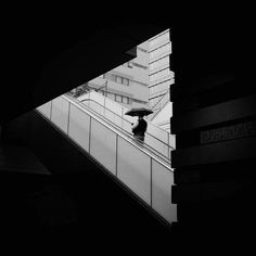 a person with an umbrella is walking down the escalator in black and white