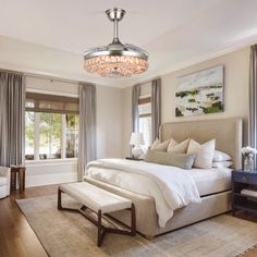 a bedroom with a large bed and chandelier hanging from it's ceiling