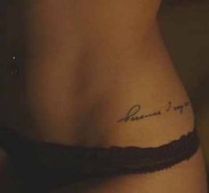 the back of a woman's stomach with a small tattoo on her left side