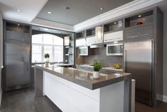 a modern kitchen with stainless steel appliances and marble counter tops, along with an island