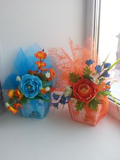 two vases filled with flowers sitting on a window sill next to each other