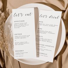 two white plates with menus on them sitting on top of a cloth covered table