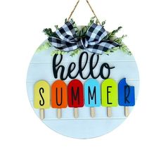 a sign that says hello summer hanging from a wall with popsicles and leaves on it