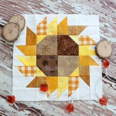 a patchwork sunflower is sitting on the floor next to some wood slices and yarn