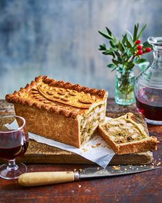 there is a pie on the cutting board next to a glass of wine