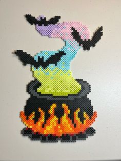 a piece of art made out of perler beads on a white surface with fire and flames