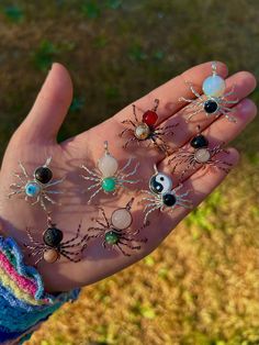 a person's hand holding several different types of spider brooches on it