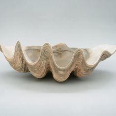 a white ceramic bowl with wavy edges on a gray background, in the shape of an ocean wave