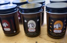 four jars of peanut butter sitting on top of a wooden table next to each other