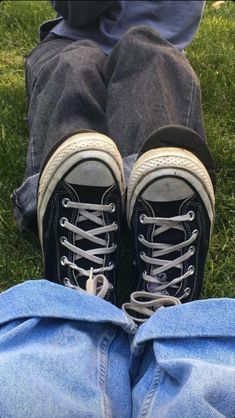 the legs and shoes of a person sitting on grass