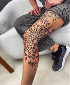 a person sitting on a white chair with a tattoo on their leg and legs that are covered in black ink