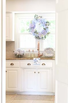 a kitchen with white cabinets and blue flowers on the window sill