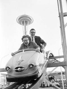 a man and woman riding on top of a roller coaster