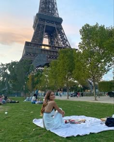 a woman sitting on the grass in front of the eiffel tower, paris