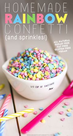 a bowl filled with colorful sprinkles next to two strawberries and a pink spoon