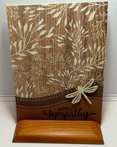 a wooden card holder with a dragonfly on it and the words sympathy written in black ink