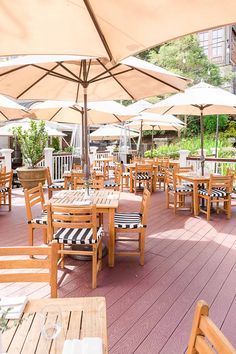 an outdoor dining area with wooden tables and chairs covered by umbrellas on a deck