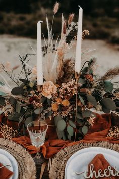 the table is set with candles, plates and napkins for an elegant fall wedding