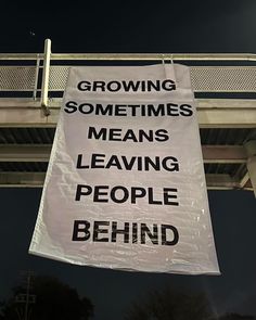 a sign hanging from the side of a bridge that says growing sometimes means leaving people behind