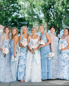 a group of women standing next to each other wearing blue dresses and holding bouquets