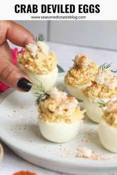 Image of six crab deviled eggs served on a white matte plate. Hand is picking up one crab deviled egg. Crab Stuffed Deviled Eggs, Lobster Deviled Eggs, Pupu Platters, Seafood Deviled Eggs, Cajun Deviled Eggs, Stuffed Deviled Eggs, Crab Deviled Eggs, Deviled Crab Recipe, Crab Deviled Eggs Recipe