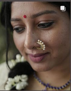 a close up of a woman wearing a nose ring with flowers on it's nose