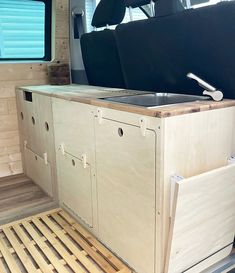 the inside of a van with wooden flooring and storage compartments on it's side