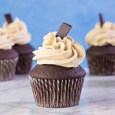 chocolate cupcakes with white frosting and an oreo stick sticking out of the top