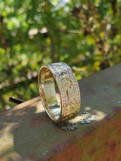 a wedding band with an intricate design on the outside and inside, sitting on top of a stone wall