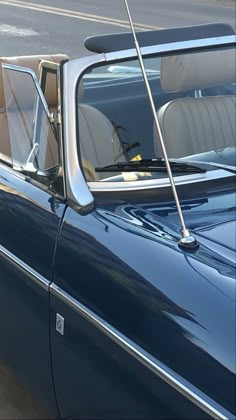 an old blue car parked on the side of the road with it's sunroof