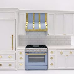 a blue stove top oven sitting inside of a kitchen next to white counter tops and cabinets